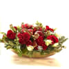 Arrangement includes evergreen brunches, red roses whit flowers 