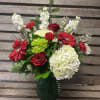 Designers choice of seasonal Christmas flowers and greens arranged in a large
