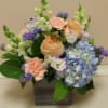 a delicate arrangement, soft peaches and blues in a twig based basket.
