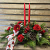 Stunning holiday centerpiece with two red taper, candles, seasonal greens, pops of