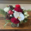 This festive arrangement masterfully blends traditional holiday elements with unexpected tropical elegance.