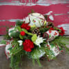 Winter greens, mums, mini carnations, cones, ribbons, and trims are crowned by