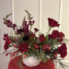 A beautiful round white vase filled with a wide array of red