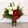 This arrangement features three roses and a gerbera daisy with greens and