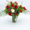 An elegant holiday arrangement featuring premium red and white roses, scarlet carnations