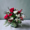 Red roses, holiday greenery, berries, pine cones and ornaments all designed in