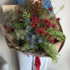 A festive and modern handheld holiday bouquet featuring striking blue and red