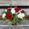 Red and White flowers arranged in evergreens, with touches of pinecones. Clear