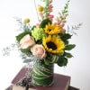 Brighten any day with sunflowers, roses, and whimsical accents. A cheerful arrangement