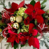 A Festive arrangement featuring vibrant red poinsettias, classic red roses,white lilies,hydrangea,seasonal greenery