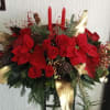 Festive arrangement with red poinsettias,roses,pine accents,candles and elegant golden details.