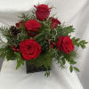 Blend of seasonal greens with red roses, pine cones, and berries to