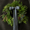The Blue Jay Wreath blends steel-blue accents with fresh evergreens, juniper, and