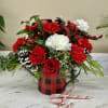 Mixed Christmas greens with red and white flowers and a decorative watering