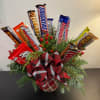 12 CANDY BARS ARRANGED LIKE FLOWERS IN A HOLIDAY THEMED CONTAINER.