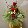 A tall vase of red and white flowers adorned by lush winter