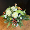 Enchanting winter arrangement featuring greens, flowers, charming deer, and frosted tree ornaments;