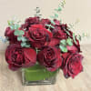 12 ROSES ARRANGED TIGHTLY IN A LOW, SQUARE VASE WITH EUCALYPTUS