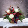 This basket arrangement has Christmas greens and frosted glitter accents