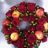 A wreath of roses, apples, and green berries