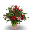 A cheerful holiday arrangement bursting with red roses, pink carnations, fresh winter