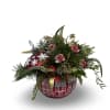 A sparkling holiday arrangement featuring festive red blooms, lush winter greens, and