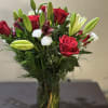 This stunning floral arrangement features lush roses and graceful lilies, beautifully accented