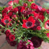 Low and lush red winter arrangement of seasonal red accents and winter
