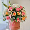Pink and peach roses arranged with white hydrangea and carnations, dollar, snapdragons.