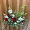 The crystal cross is nestled elegantly among red and white blooms, this