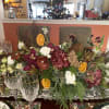 A bold, modern centerpiece bursting with rich maroon tones, delicate orchids, and