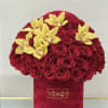 Elegant red roses overflow in a luxurious hat box, adorned with golden