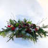 Our signature 2025 textural centerpiece designed with evergreen sprigs, magnolia leaves, red