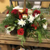 A centerpiece with a mixture of Christmas greens and other flowers and