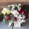 An abundance of holiday greens accented berry decorations, lush red roses, white