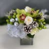 This elegant design of white roses, green cymbidium orchids, cedar, pine cones