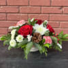 Celebrate the holidays with this cheerful centerpiece featuring roses, carnations, chrysanthemums, berries