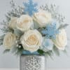 A delicate winter-inspired arrangement featuring white roses, icy blue snowflake accents, and
