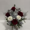 A delicate seasonal floral arrangement that blends red and white blooms with