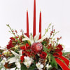 This lovely centerpiece featuring roses, orchids, lilies, berries, evergreen, pine cones, ornaments