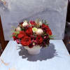 This arrangement consists of burgundy blooms, red roses, and evergreen foliage with