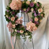 Pink hydrangea, lavender mums, and pink roses nestled in greenery and tied