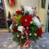 A ceramic container with lid filled with Christmas color carnations, white mums