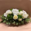 A low rectangular centerpiece incorporating mounds of white hydrangea, green trick dianthus