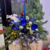 An elegant and modern holiday centerpiece designed with fresh winter evergreens, striking