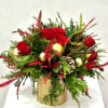A luxurious holiday centerpiece featuring classic red roses nestled among fresh evergreen