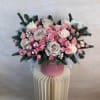A soft blush winter arrangement designed with pink and ivory roses, spray