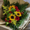 Red Roes, Sunflowers and greenery wrapped in brown floral paper in vase.
