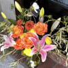 A radiant blend of coral roses, pink lilies, and sunny yellow blooms