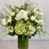 Tall green and white arrangement of premium blooms in a tall vase.